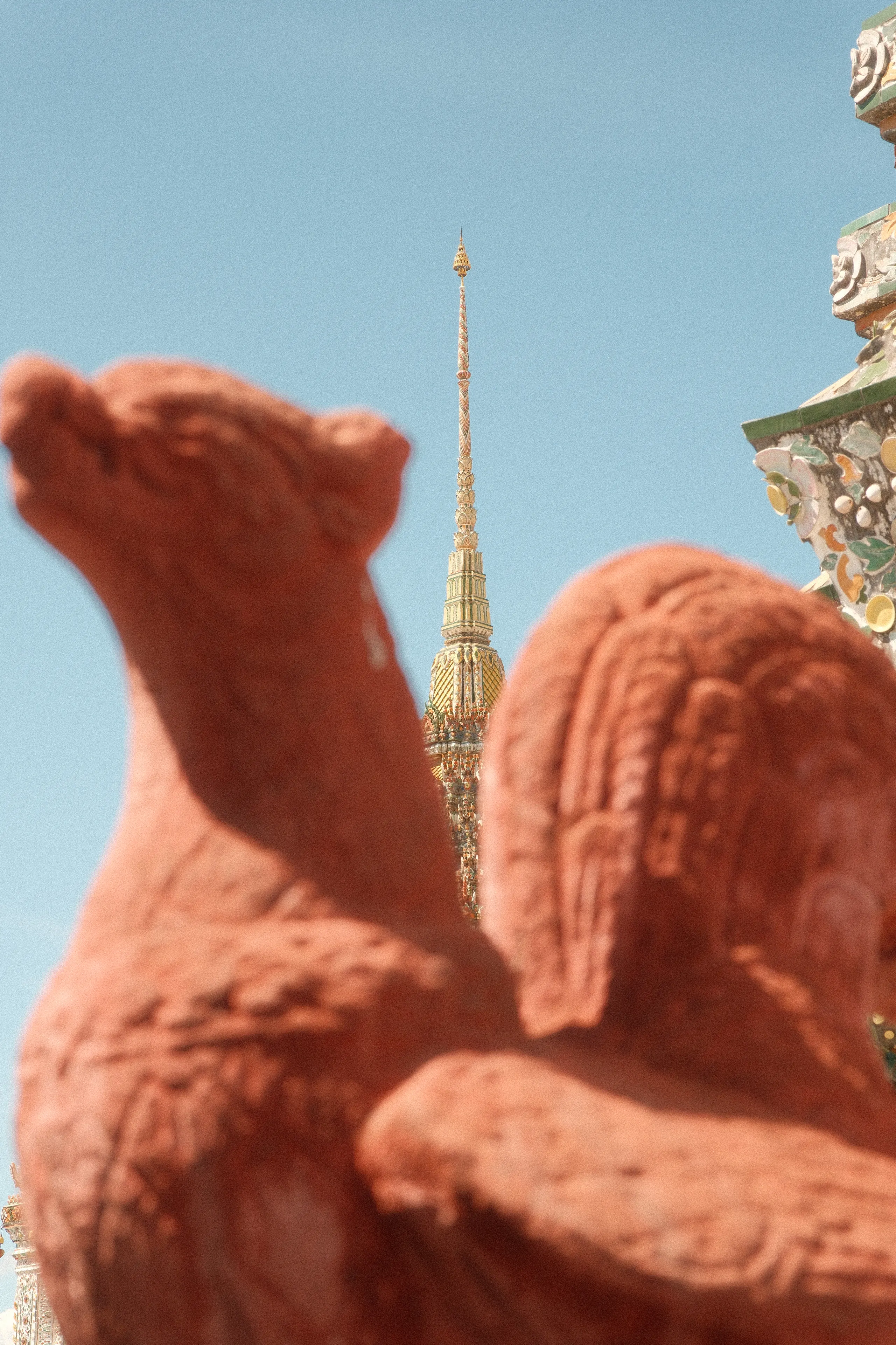 A terracotta figure in front of a spire at Wat Arun