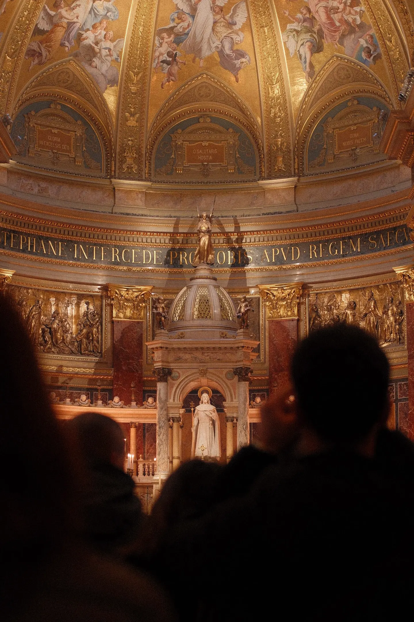 The gilded dome and altar of St. Stephen's Basilica, visitors in silhouette