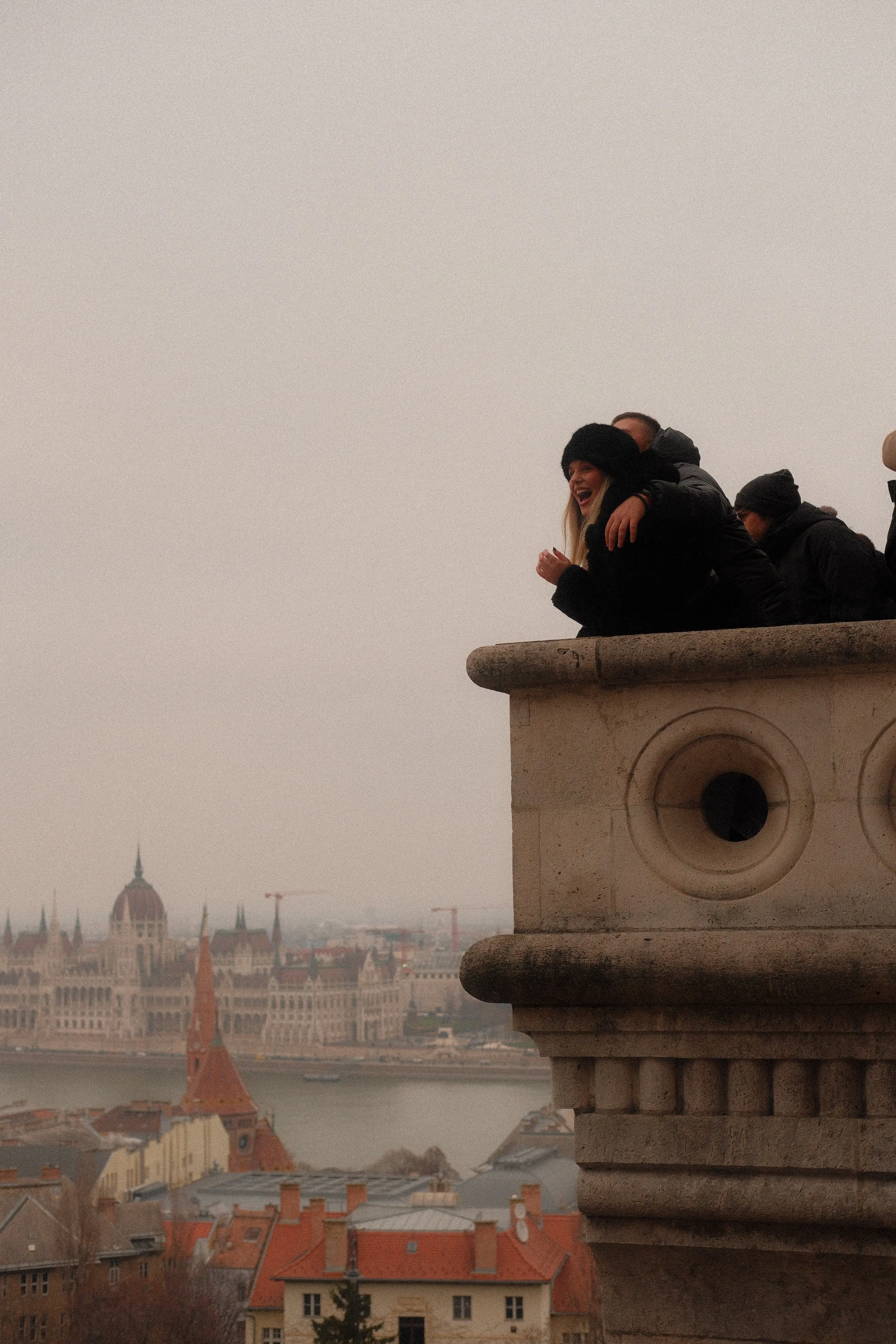 Visitors at a balustrade of Fisherman's Bastion, Parliament across the Danube
