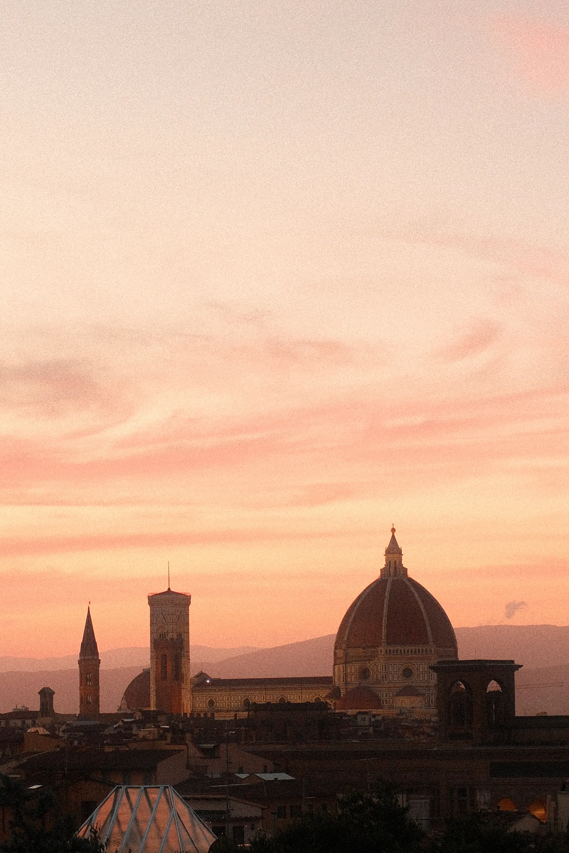 Florence's Duomo and bell towers against a pink sunset
