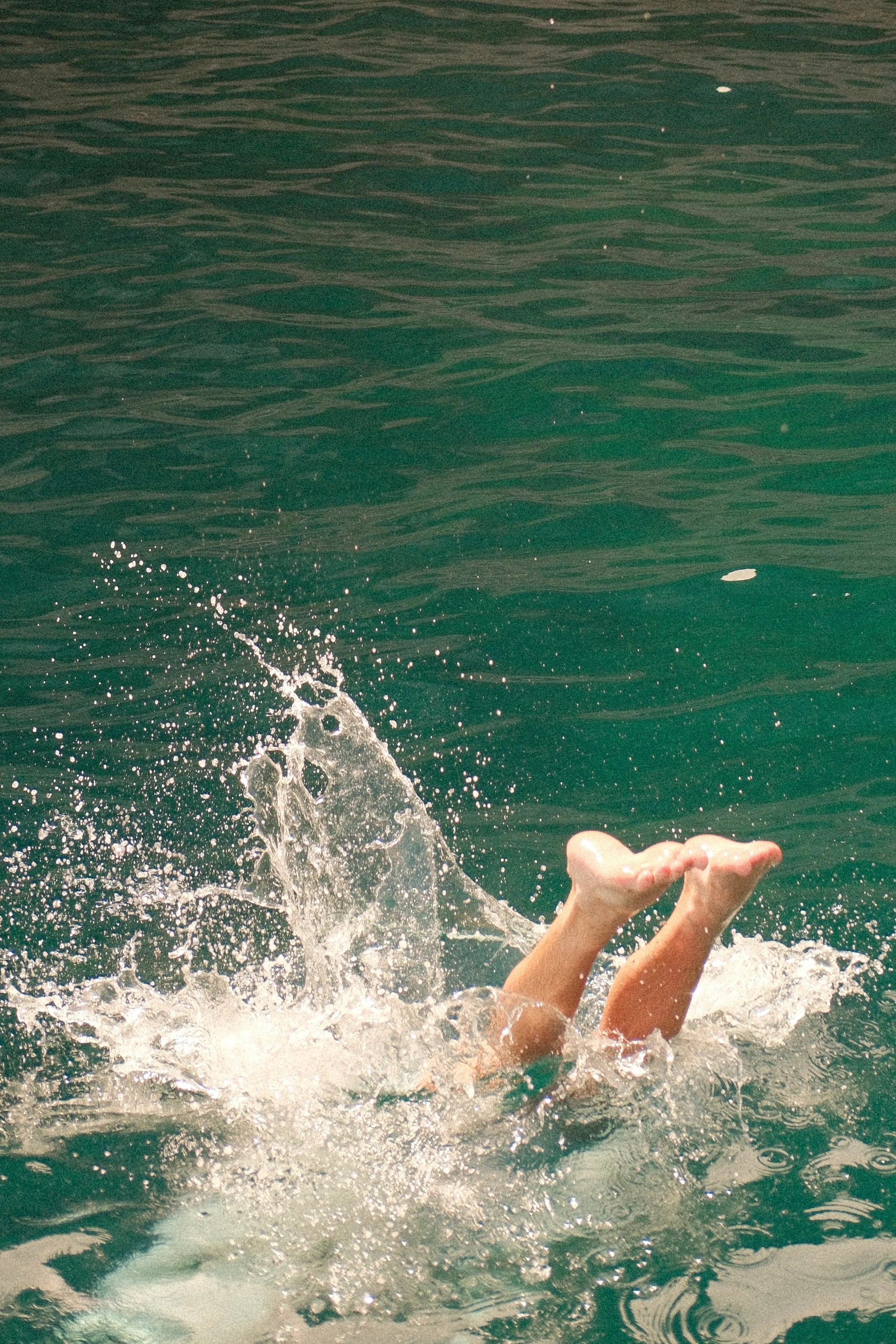 A swimmer's legs disappearing into a splash of green water
