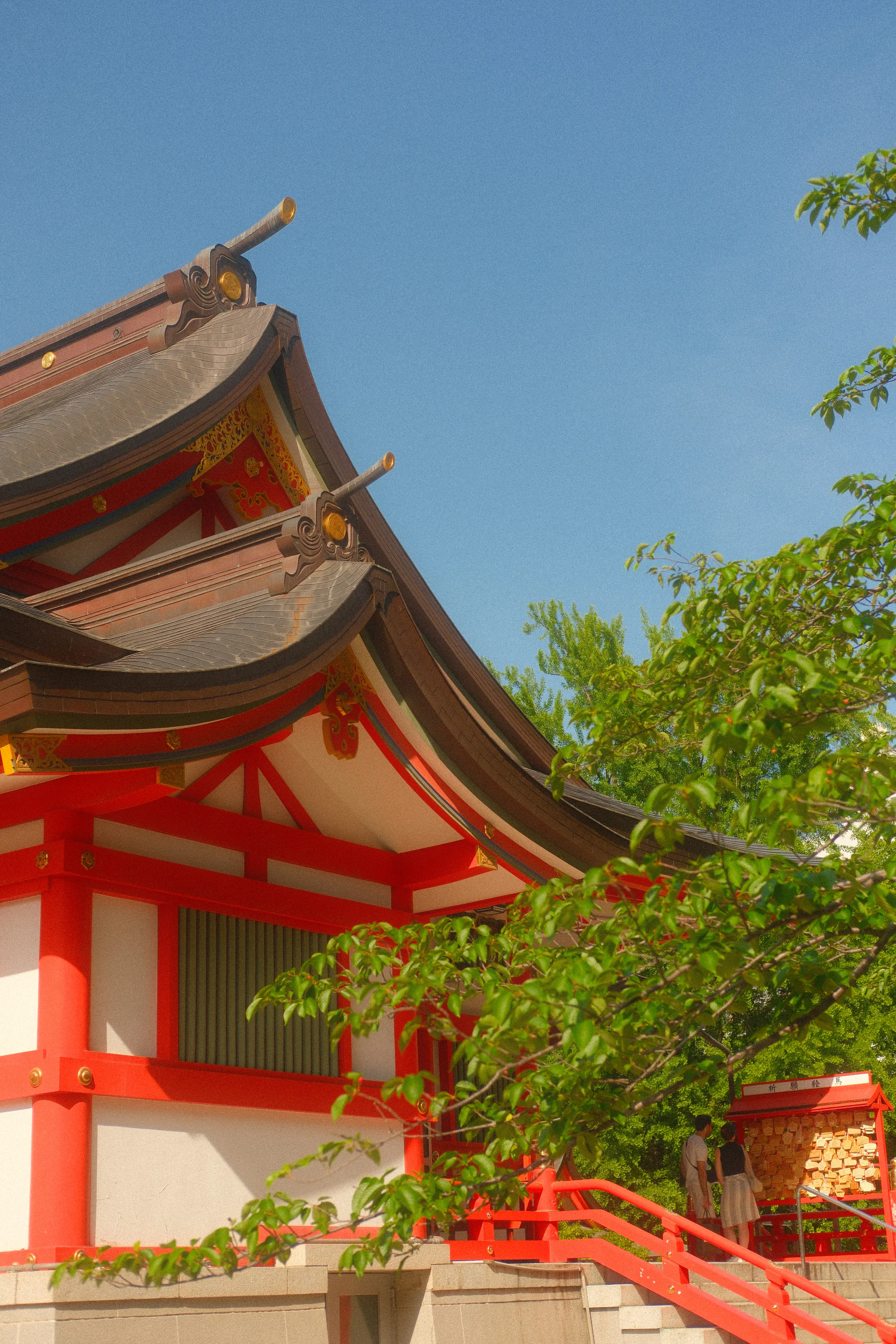 The red eaves of a shrine against a blue sky