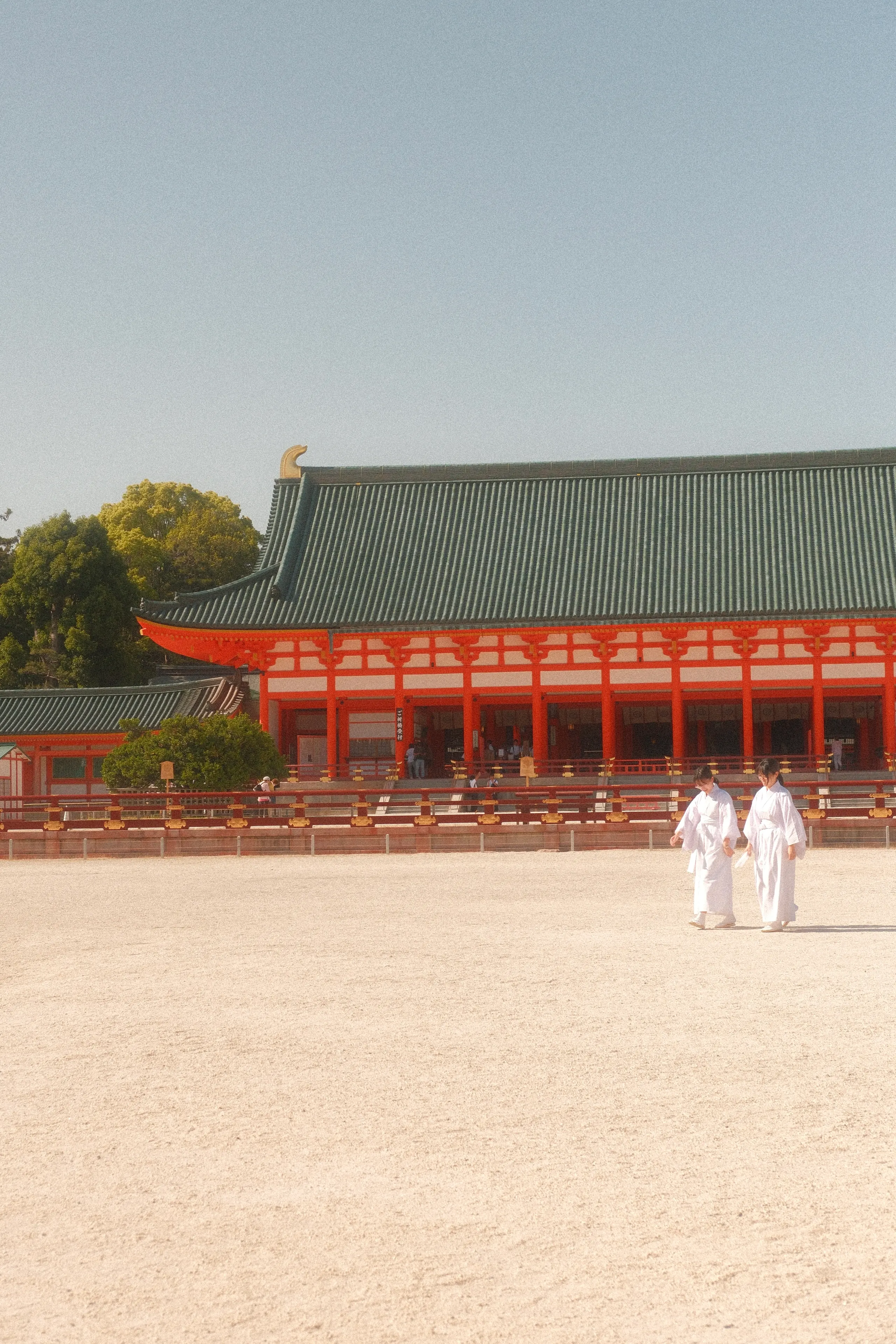 Two figures in white crossing the courtyard of Heian Shrine