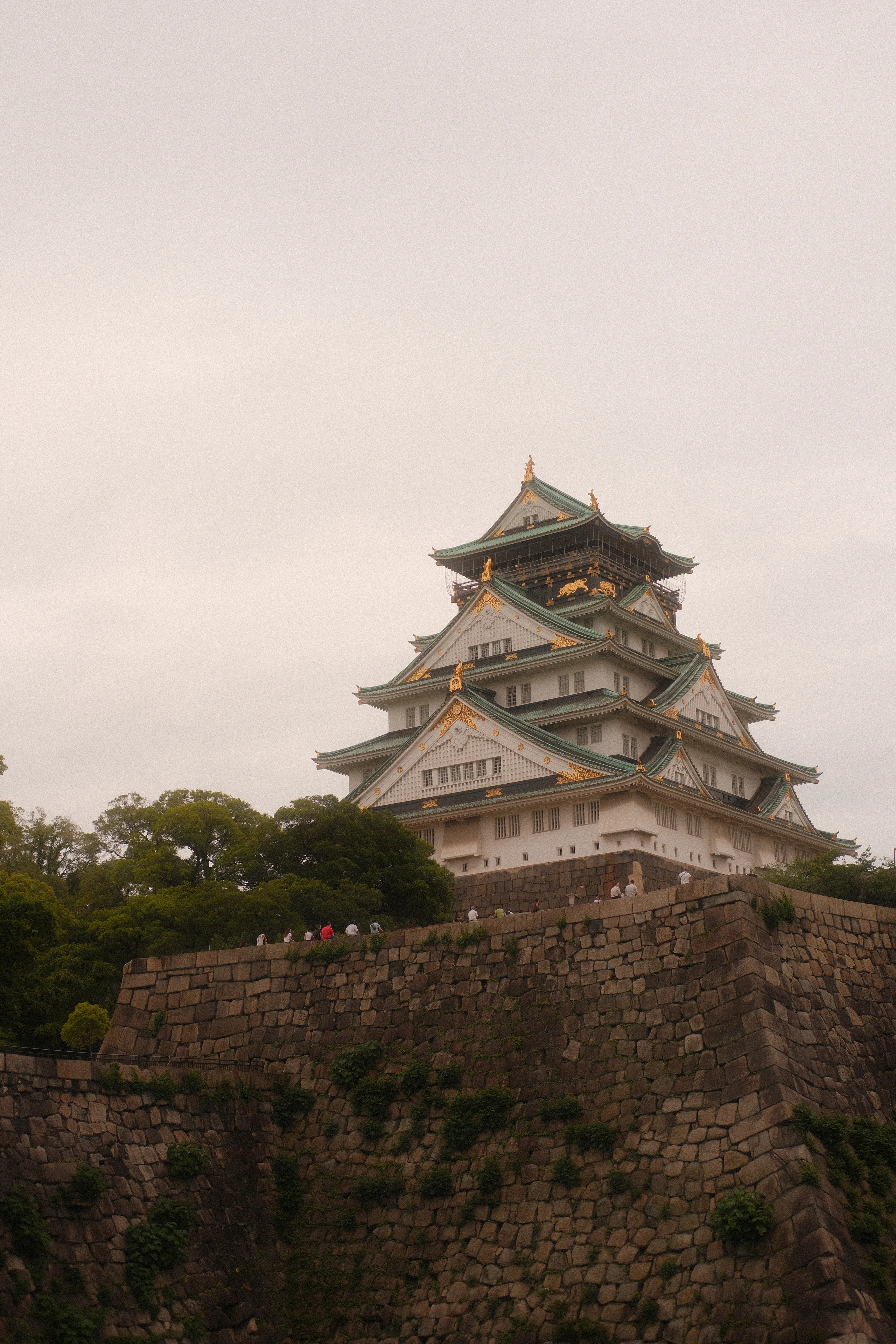 Osaka Castle above its stone walls on an overcast day