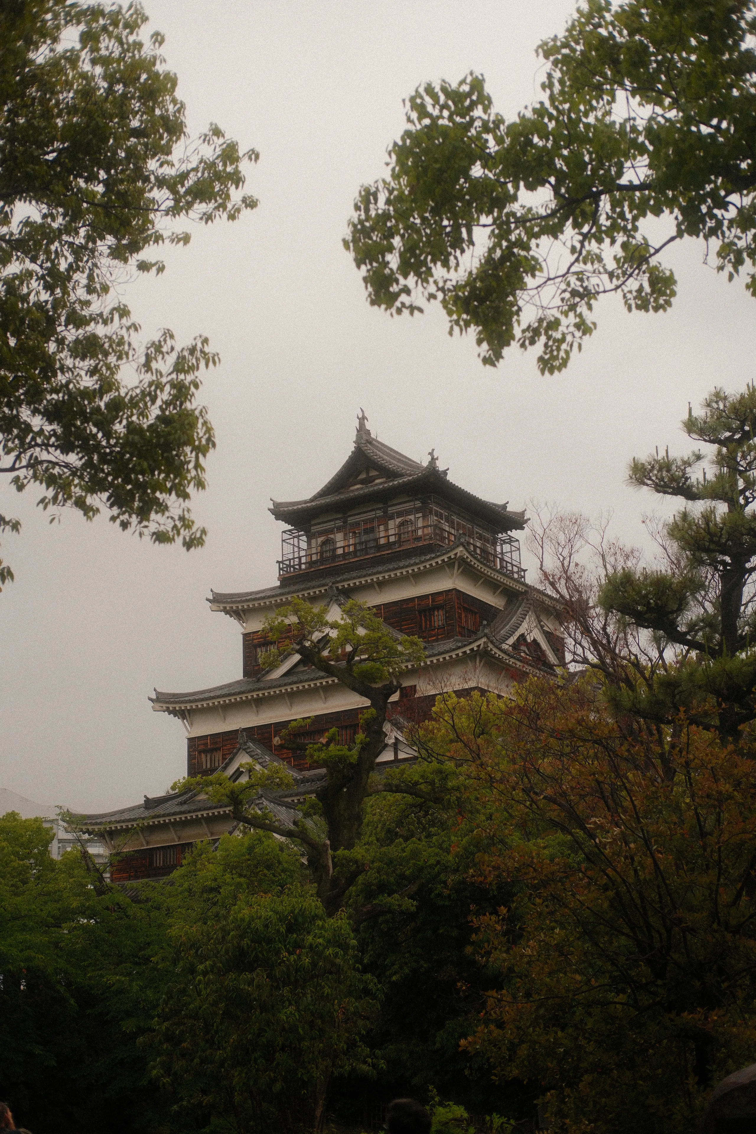 Hiroshima Castle among trees on a grey day