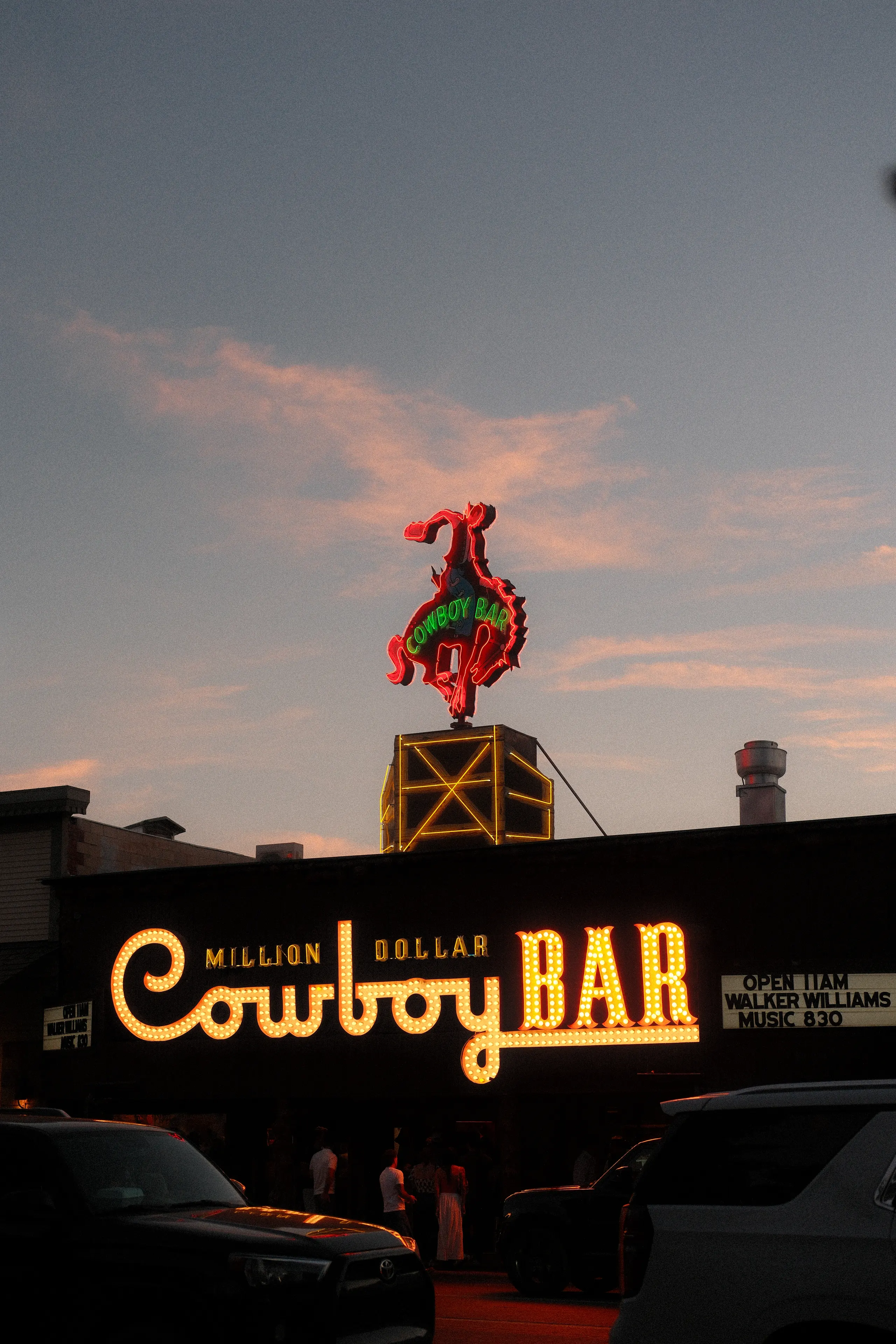 The neon cowboy sign of the Million Dollar Cowboy Bar in Jackson at dusk