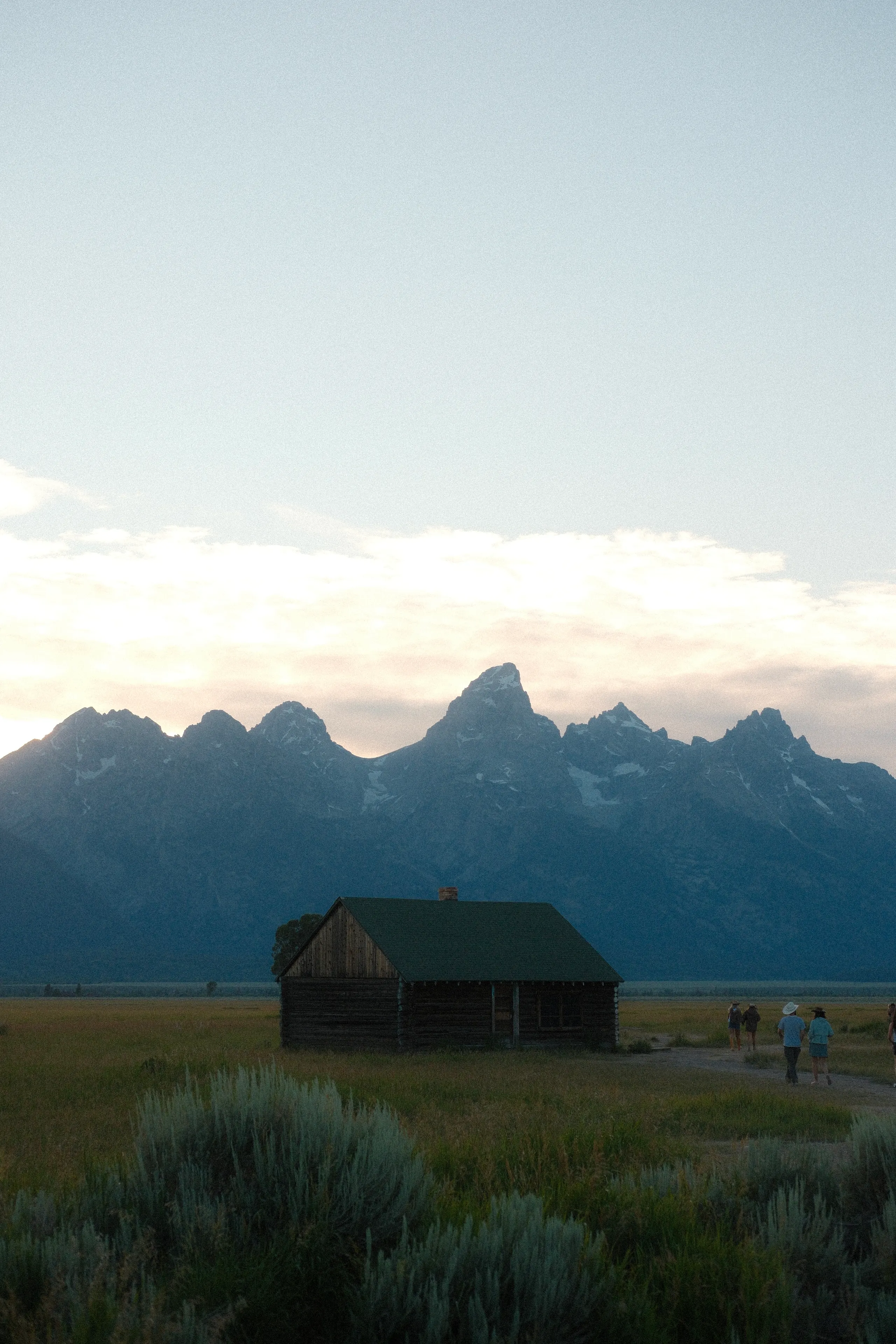 A log cabin in the sagebrush below the Teton Range