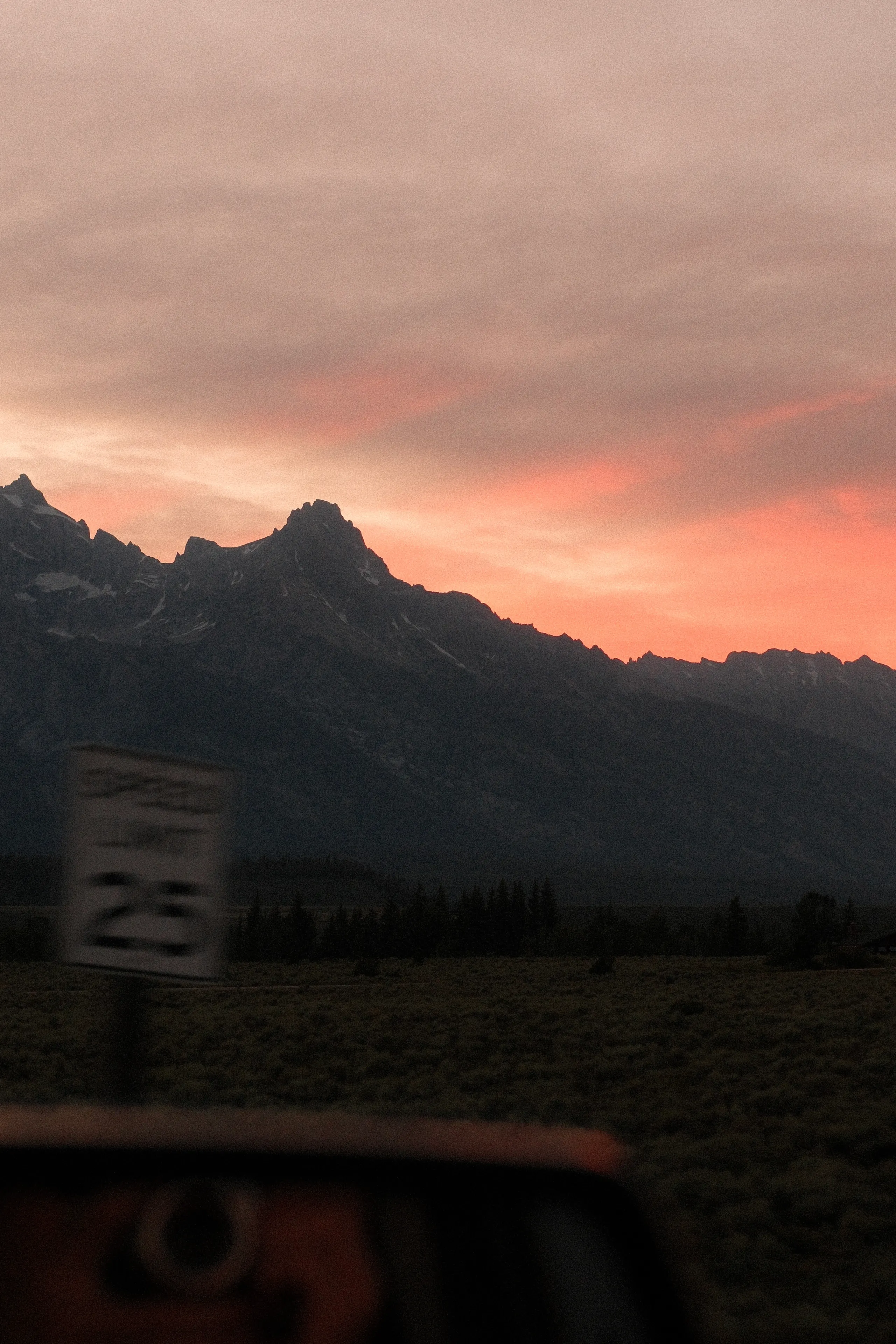 The Teton Range at sunset from the road, a speed limit sign in the foreground